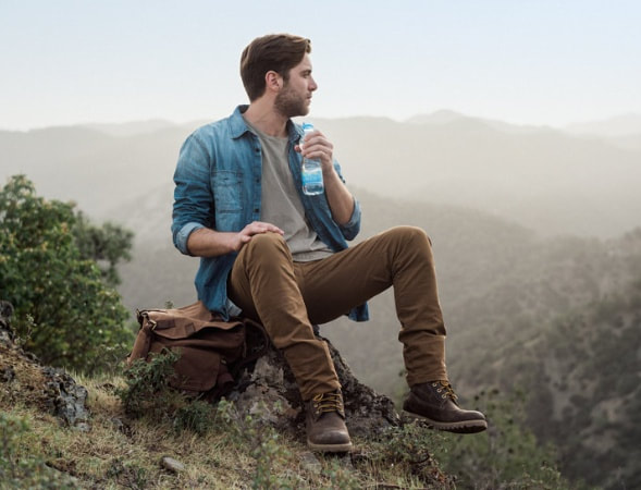 A man sitting on top of a mountain drinking water. | The White Leaf 