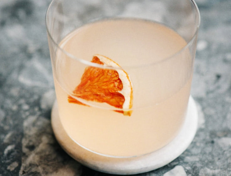 A cocktail with a slice of orange in it. | The White Leaf 
