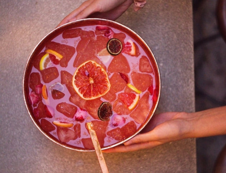 A person holding a bowl of blood orange punch. | The White Leaf 