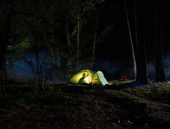 A tent is lit up in the woods at night. | The White Leaf 