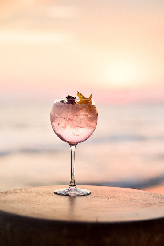 gin and tonic cocktail with a back drop of the sun setting