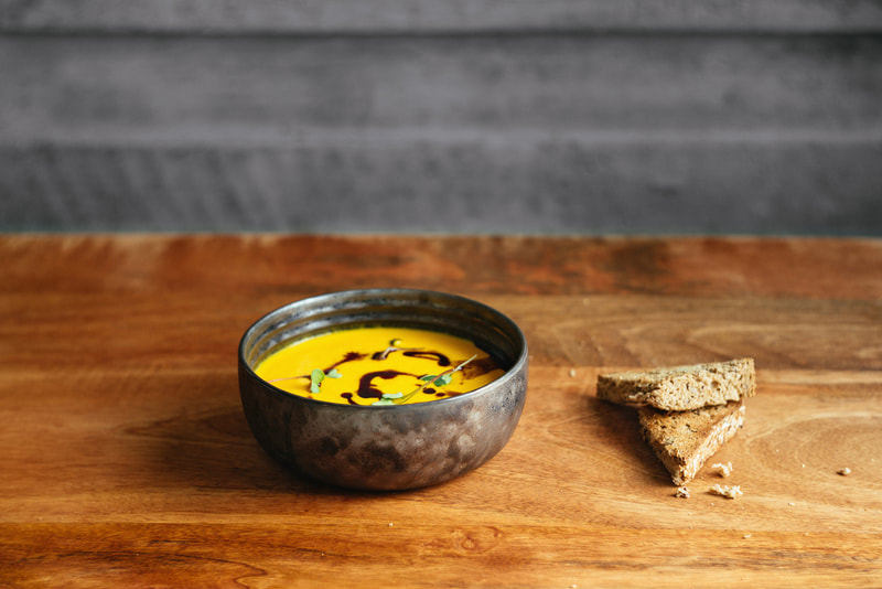 butternut soup in a bowl on a wooden board and whole wheat bread