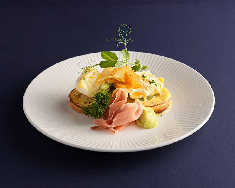 breakfast toast with ham and vegtables on a plate placed on a blue background
